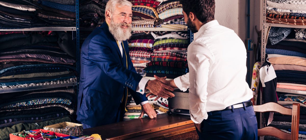 portrait-smiling-senior-male-fashion-designer-shaking-hands-with-customer-his-shop (1)
