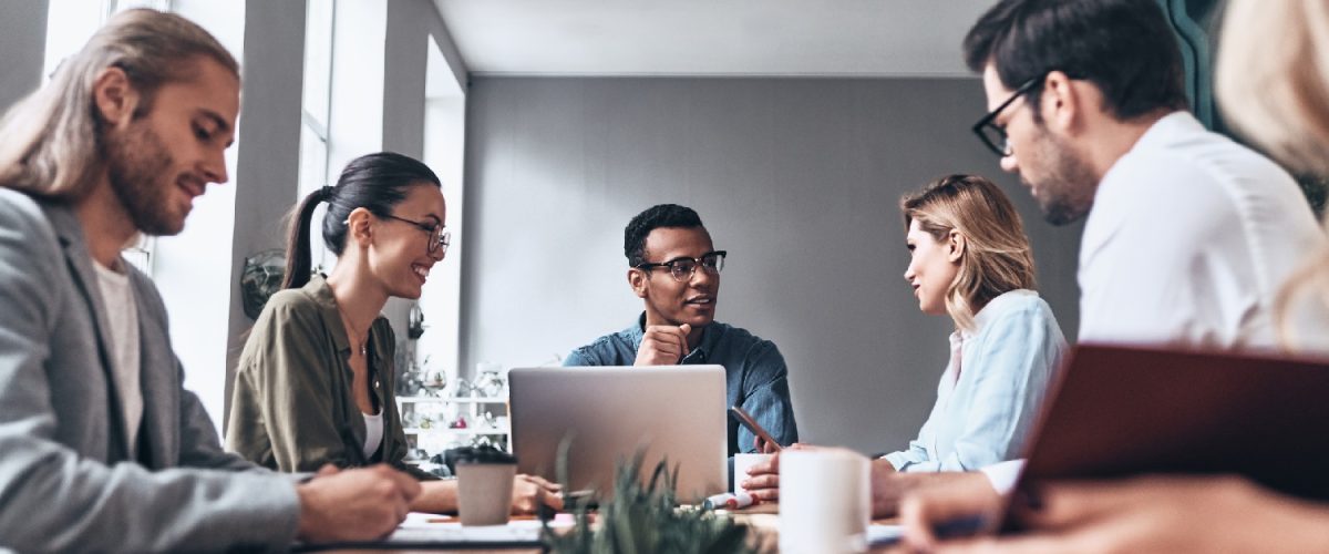 Group of young modern people in smart casual wear discussing business while working in the creative office